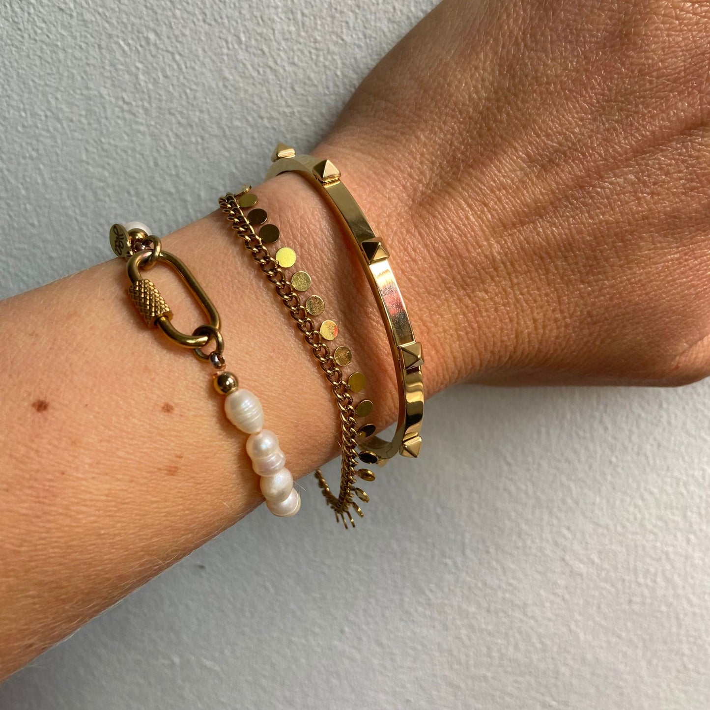 Close-up of a wrist adorned with multiple gold bangles, featuring the Gold Studded Bangle by Scott-Samuel