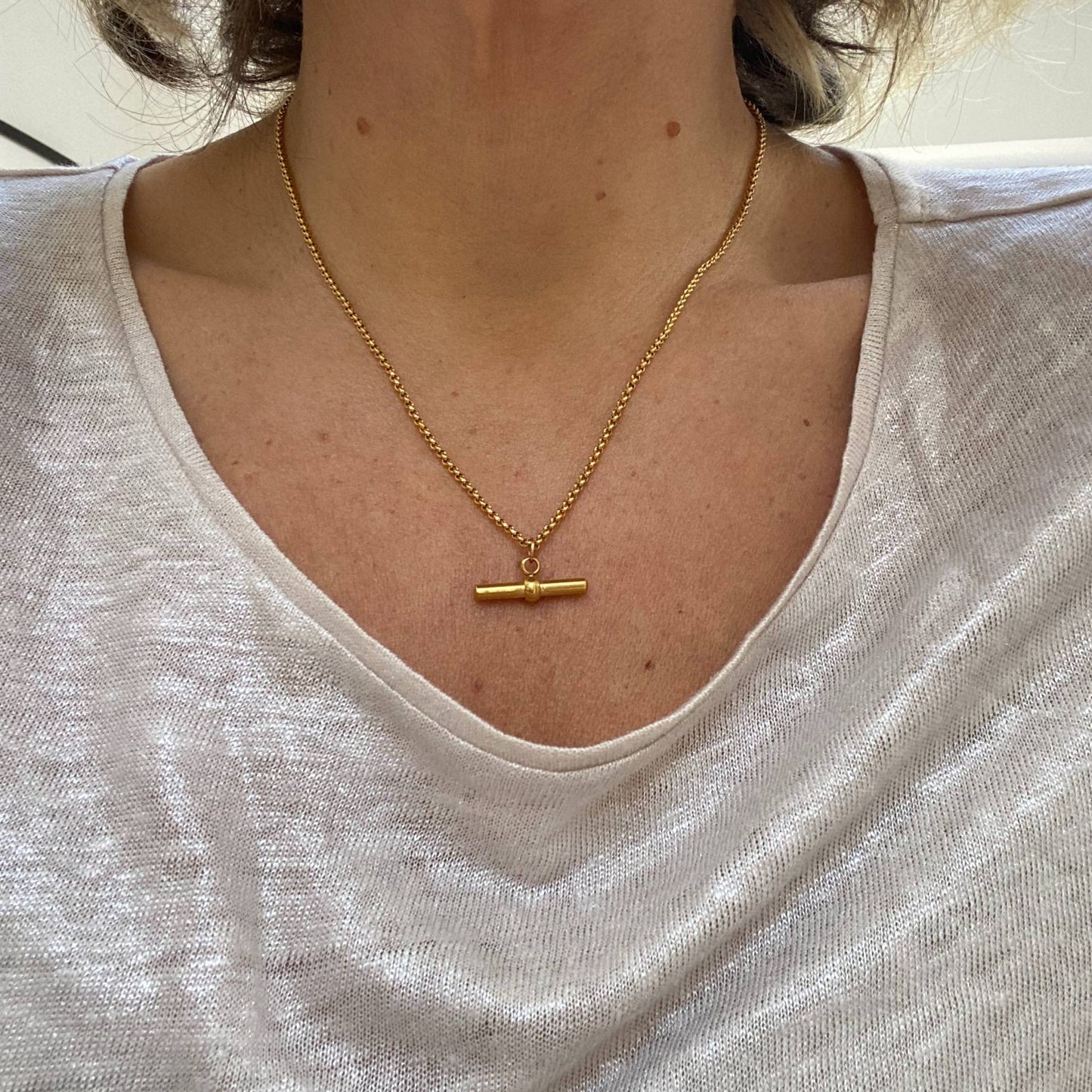 Model wearing the Gold T Bar Chain Necklace by Scott-Samuel, showcasing its elegant design