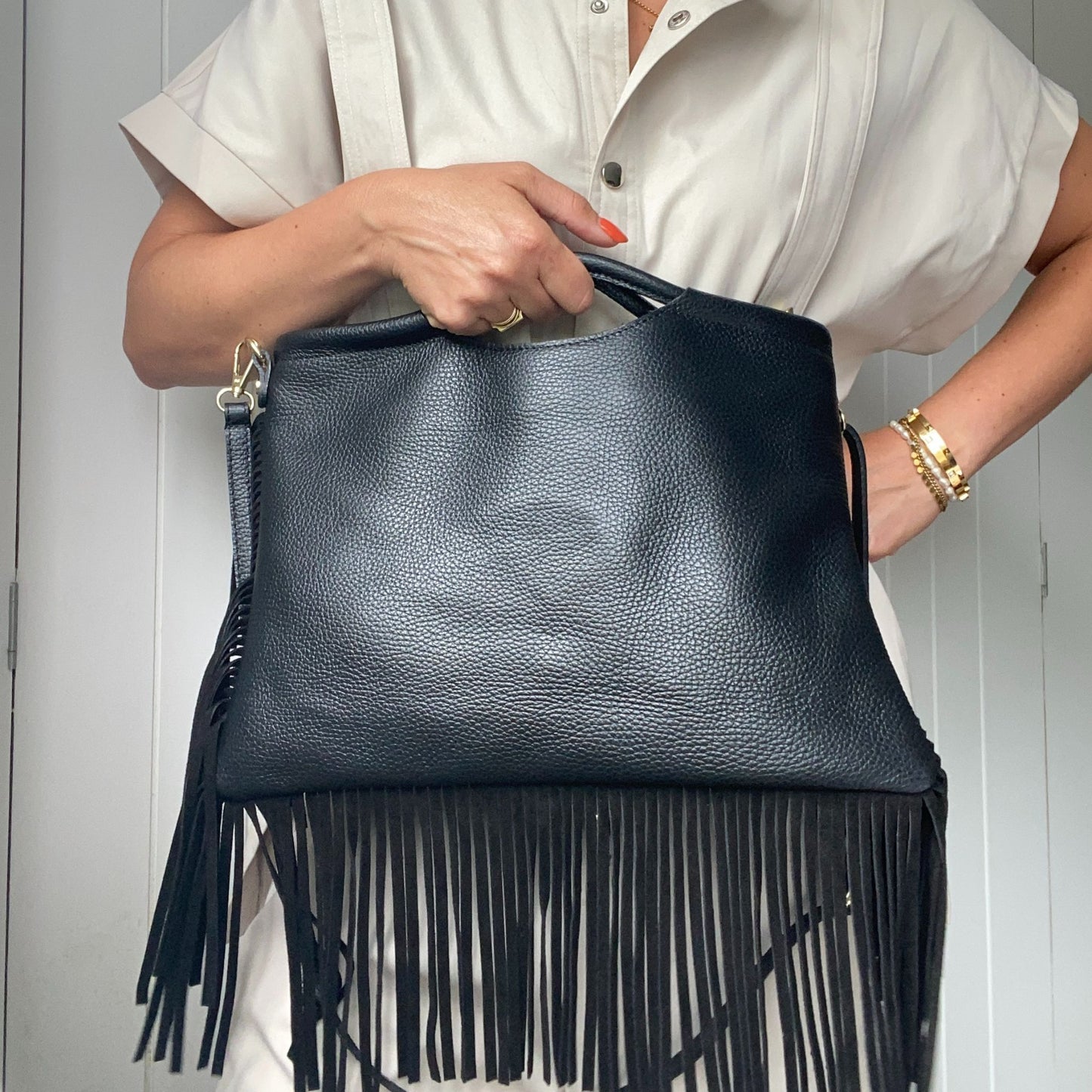 Model holding the fringed bag, showcasing its size and style.