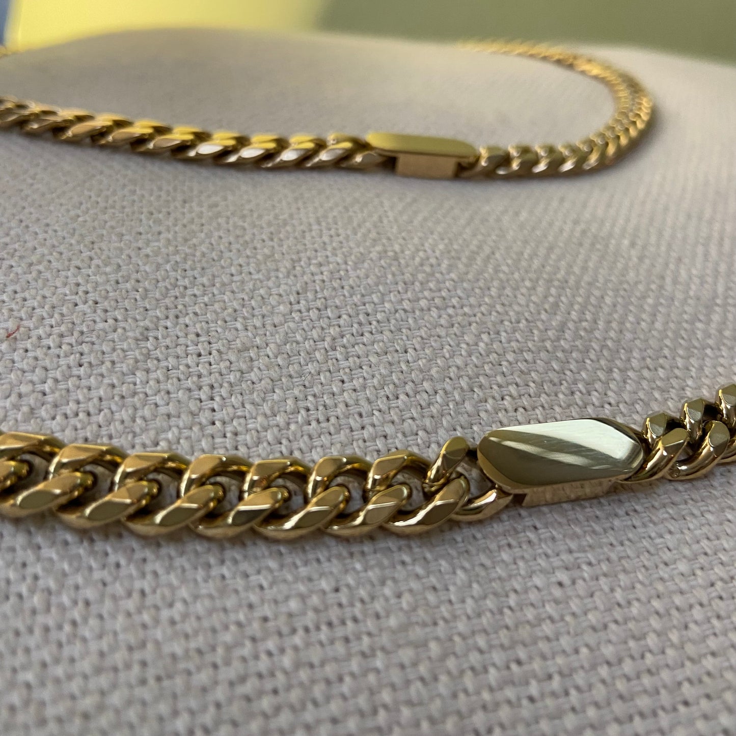 Chunky gold chain bracelet laid flat on a white background