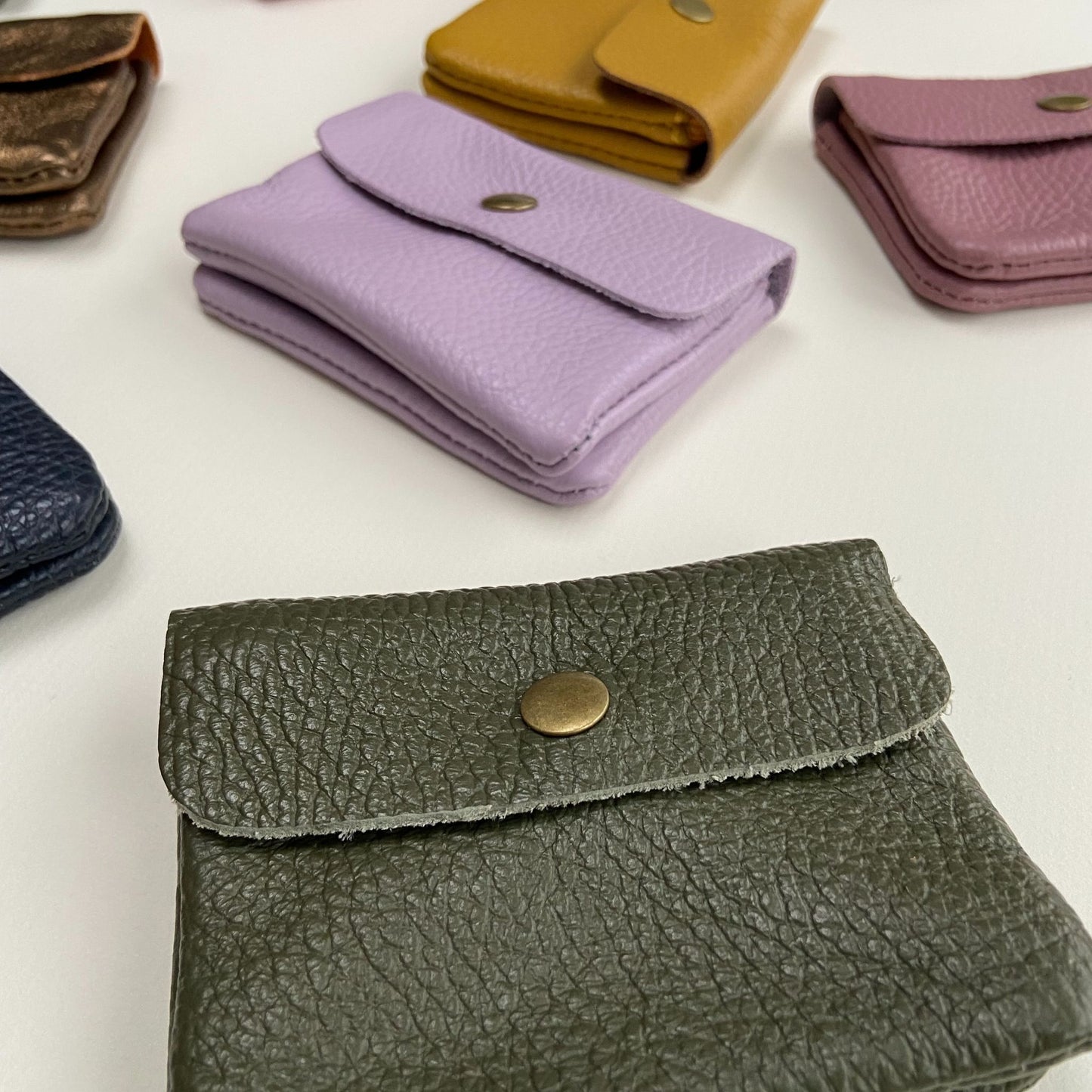 Close-up view of pink and green small leather purses showing the texture and quality
