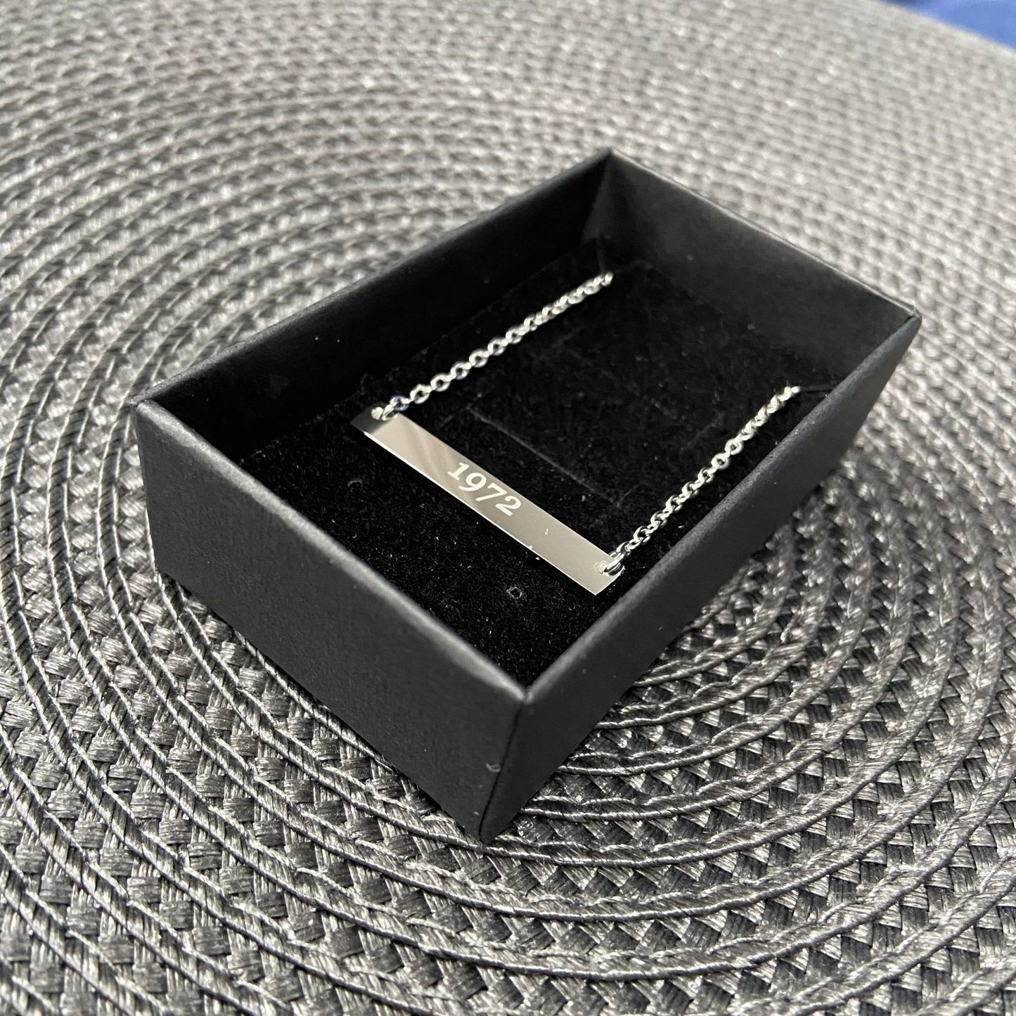 Silver bar necklace displayed in a black gift box with a soft fabric lining.