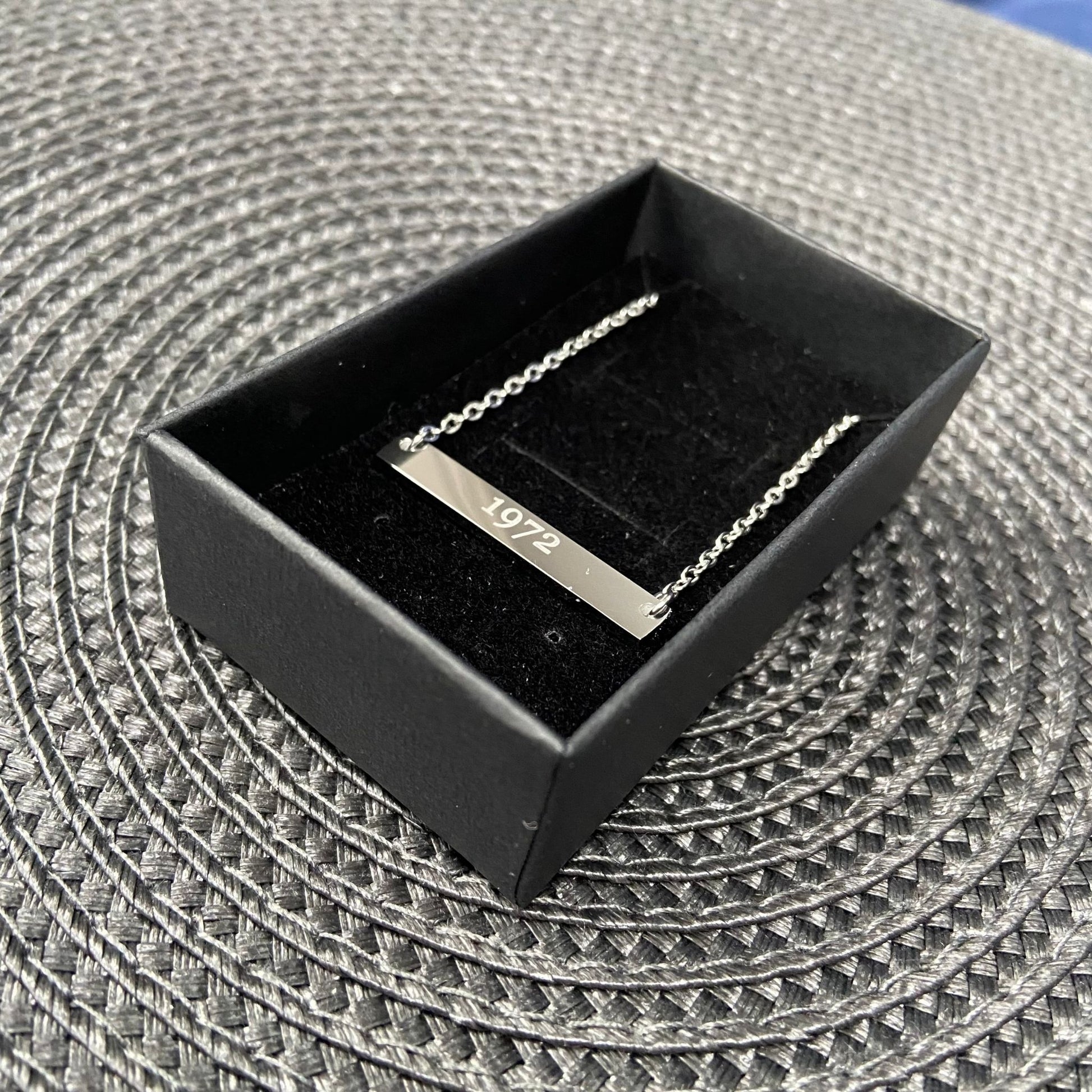 Silver bar necklace displayed in a black gift box with a soft fabric lining.