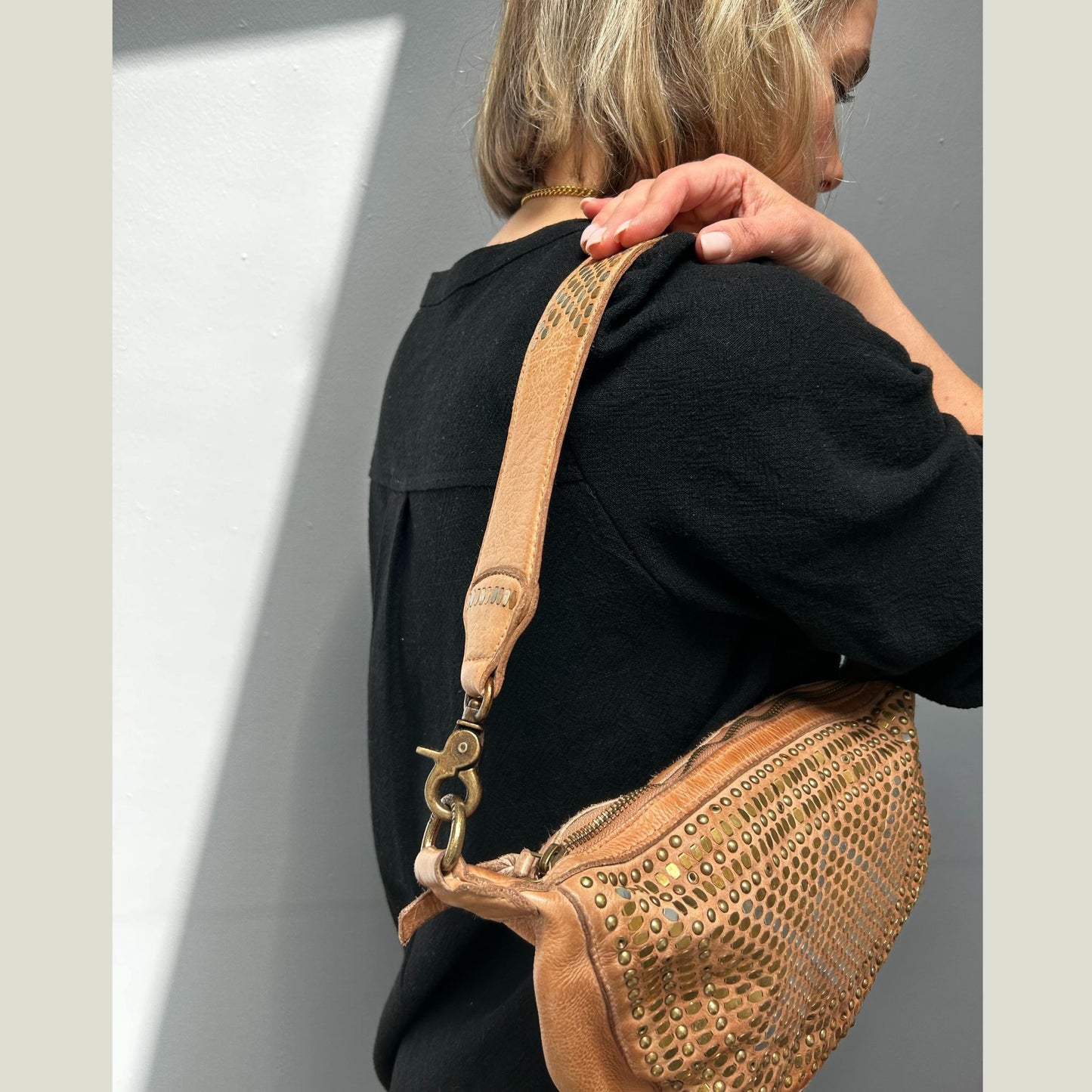 Person wearing a tan woven leather crossbody bag from Scott-Samuel over the shoulder