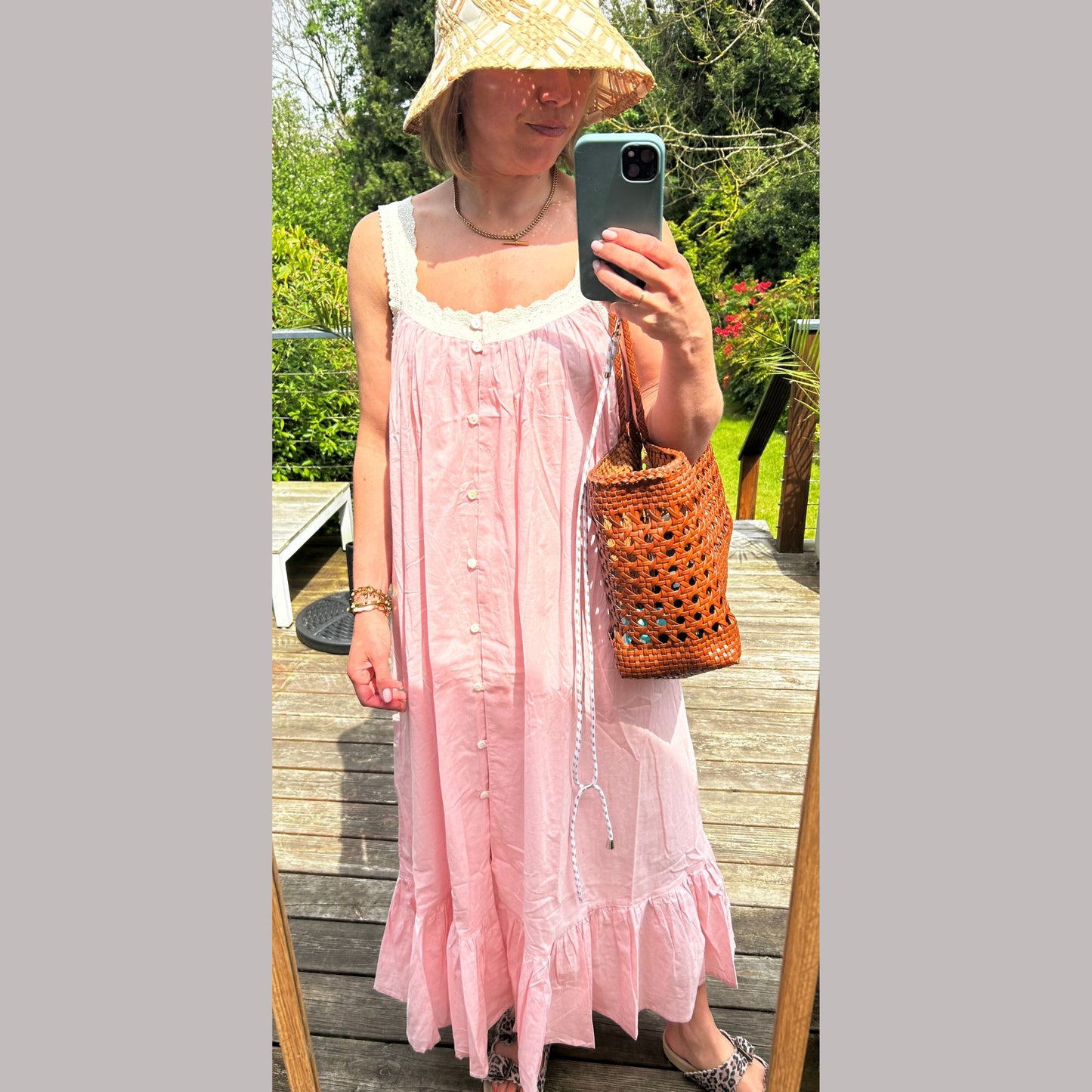 Model wearing the Pink Vintage Style Sundress/Nightdress with a sunhat, standing in a garden