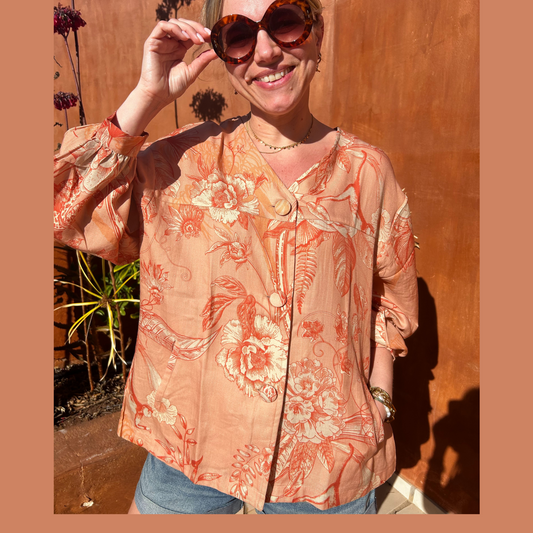 Model wearing the Coral Puff Sleeve Jacket and sunglasses, standing outdoors with a smile