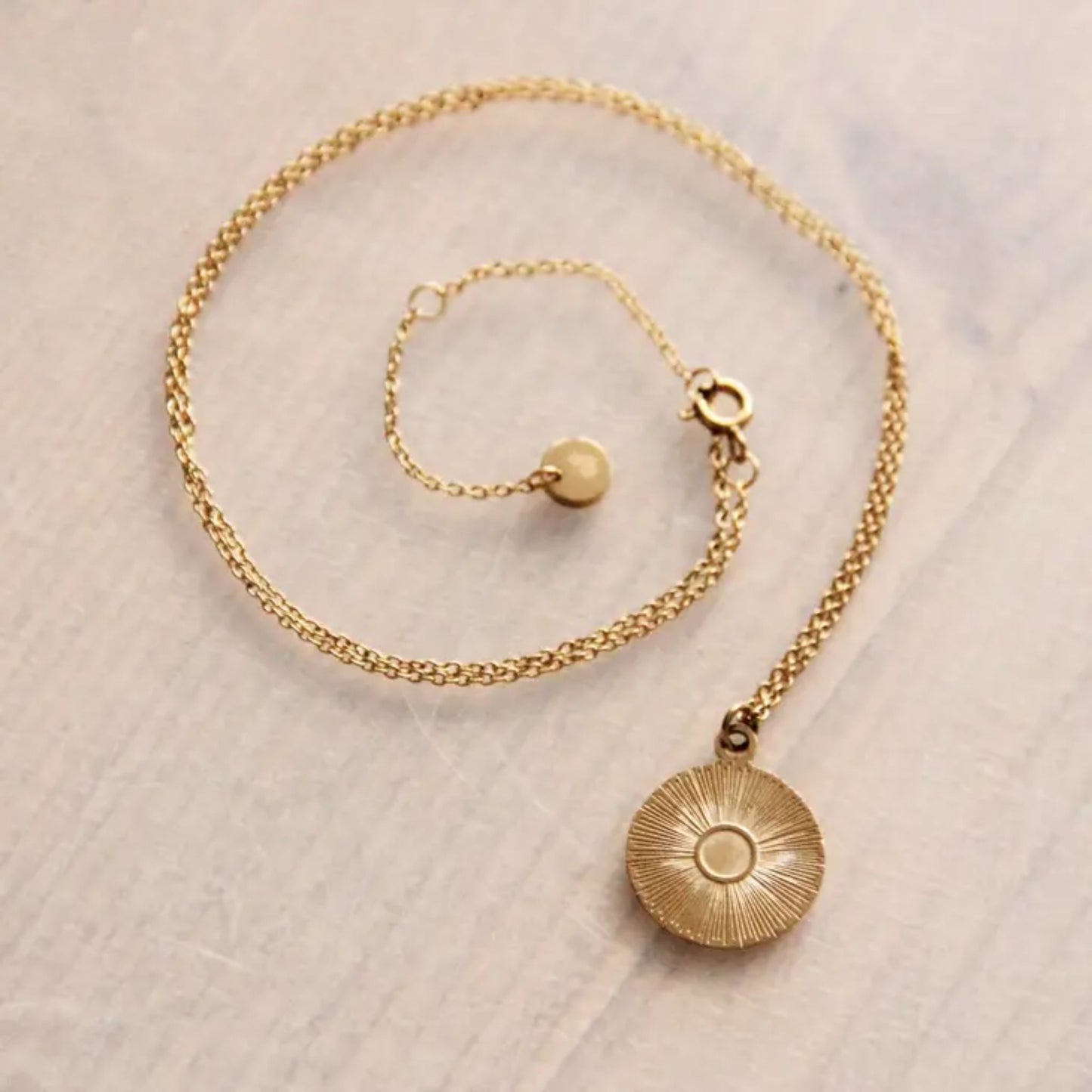 Gold Sun Pendant Necklace by Scott-Samuel displayed flat on a light background