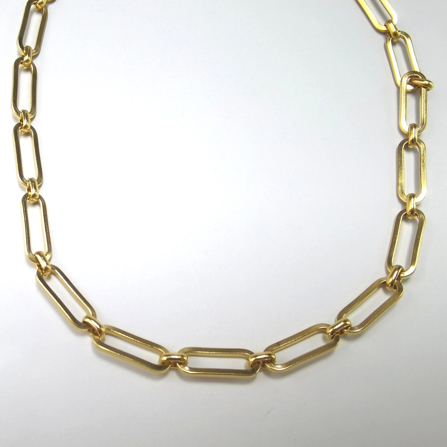 Chunky gold paperclip chain necklace laid flat on a white background