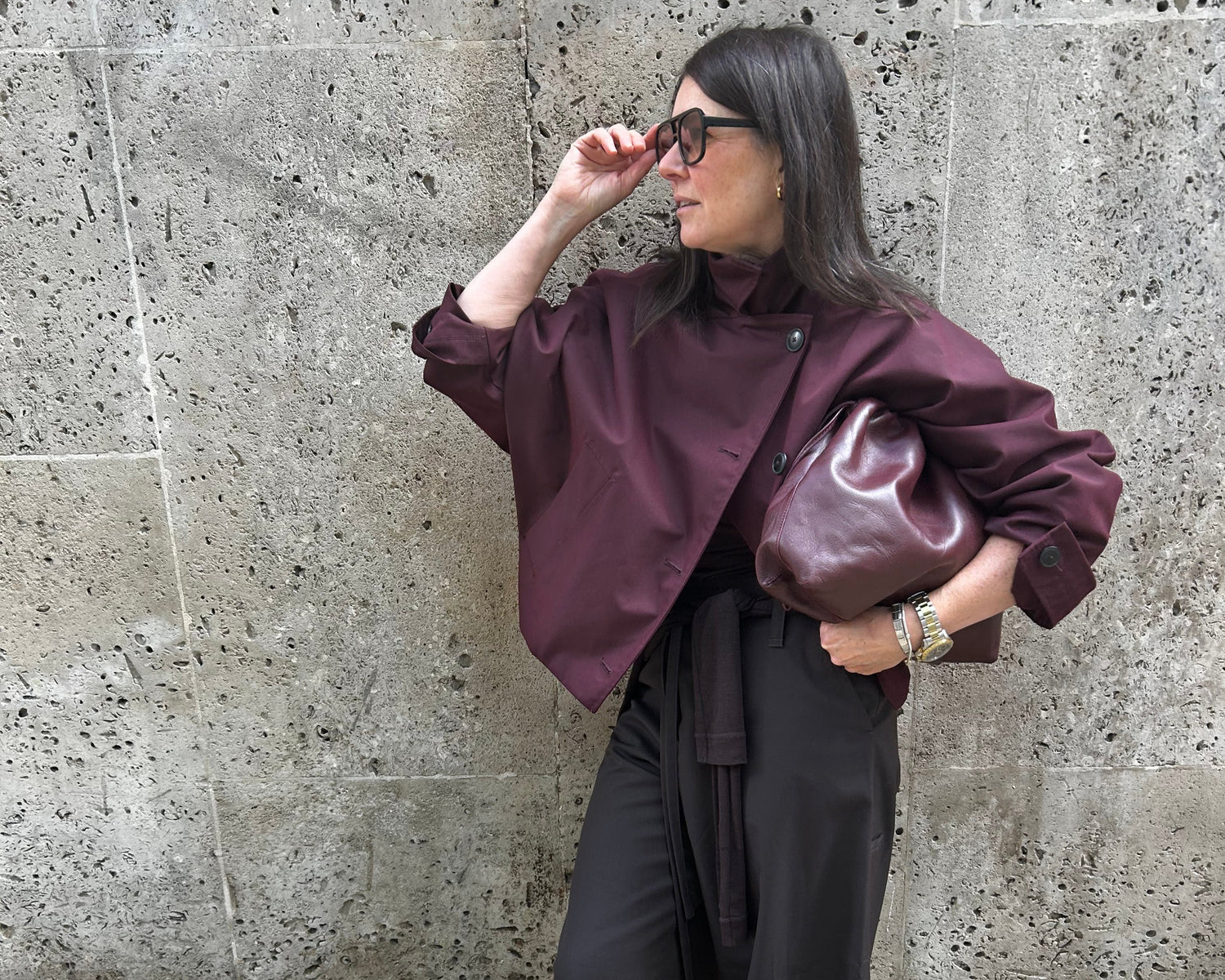 Person wearing a maroon jacket and black pants on a stone pavement