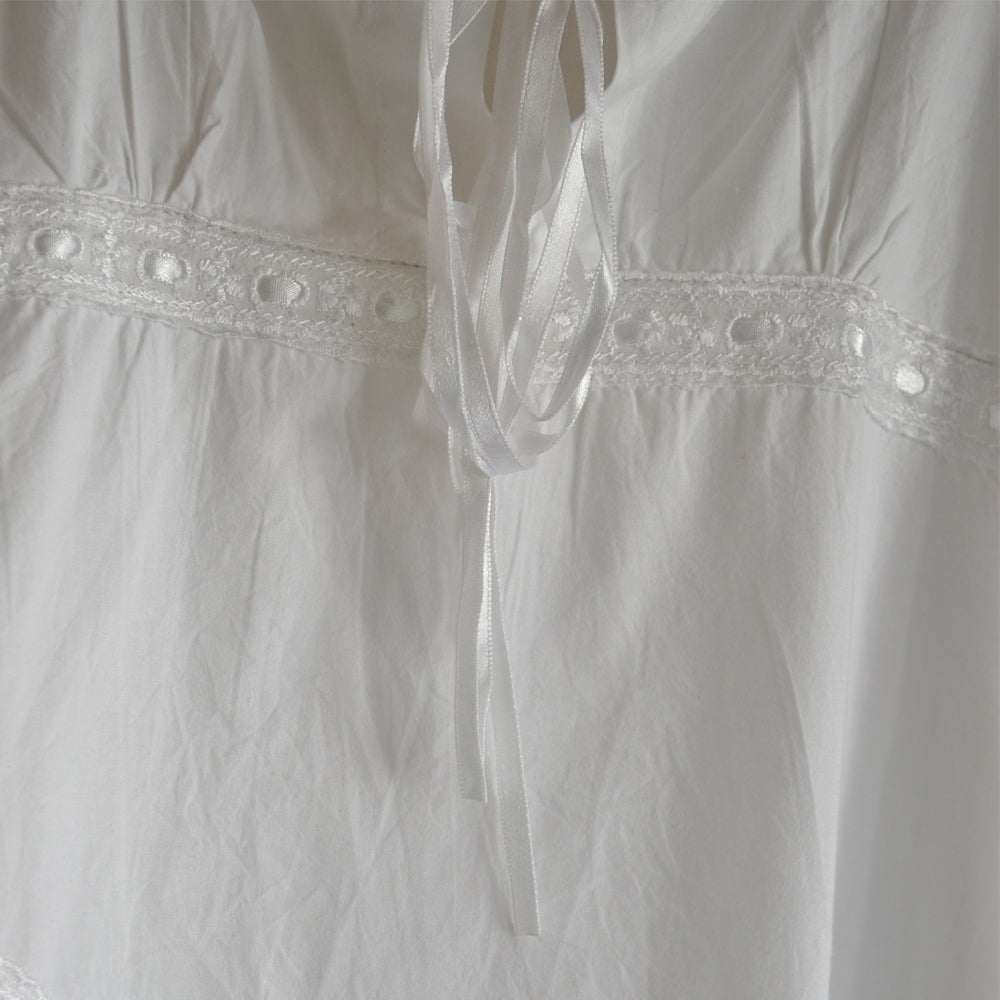 Close-up of the Broderie Anglaise detail on the straps of the white sundress/nightdress.