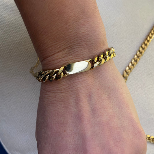 Close-up of wrist wearing a chunky gold chain bracelet.