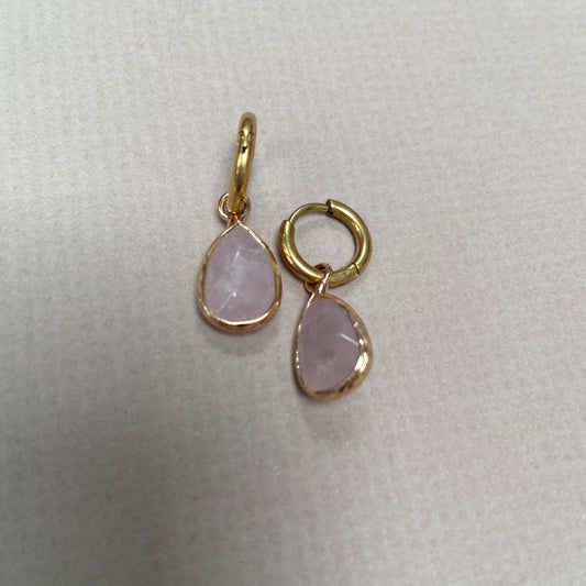 Pair of gold hoop earrings with dangling pink stones, displayed on a light background.