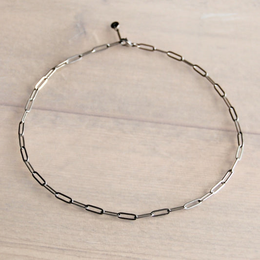 Silver chain necklace displayed on a light wood surface