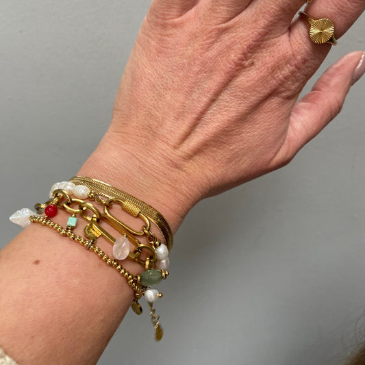 Close-up of a wrist adorned with multiple gold bracelets, featuring the Gold Snake Chain Bracelet by Scott-Samuel